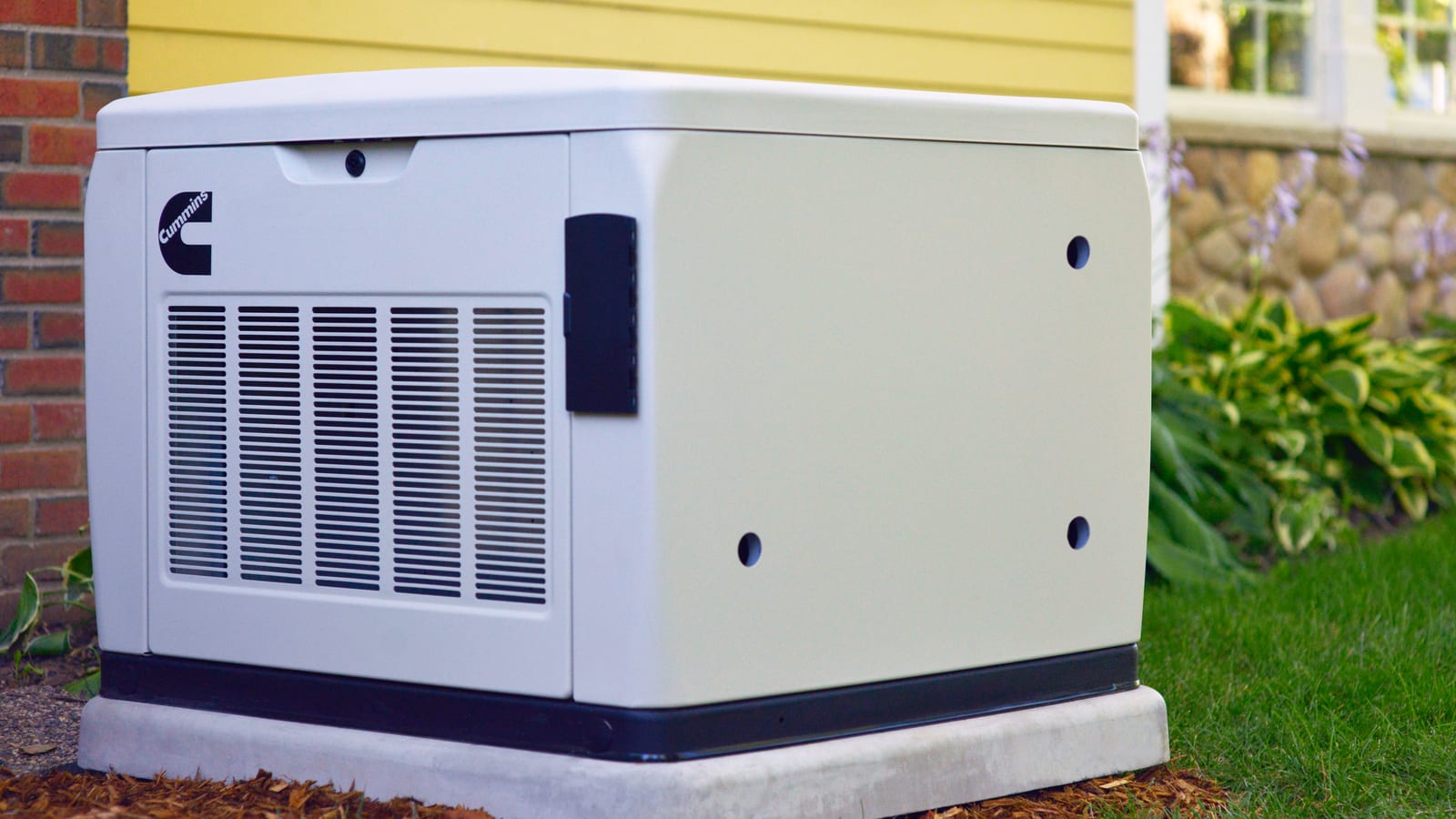 Cummins air-cooled home standby generator on a pad beside a home