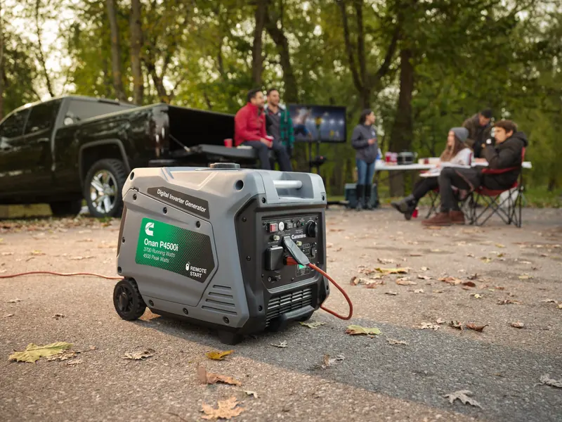 Cummins Onan P4500i portable inverter generator running on an extension cord at a tailgate
